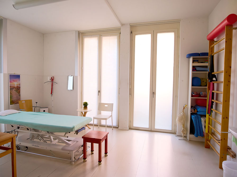 Behandlungsraum mit Therapieliege und Trainingsgeräten